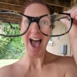 A goofy picture in which Nikki is holding her glasses closer to the camera, which makes her face look distorted, and she's carrying a look of delight.