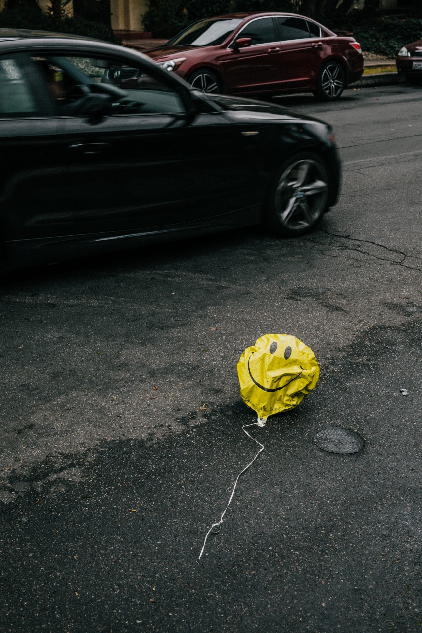 There is a deflated happy face balloon on the road.